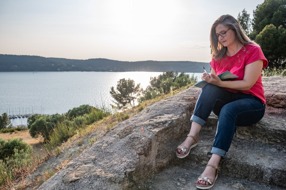 Photo de Lydie Vial écrivant dans son journal intime ouvert avec un stylo, symbolisant l'écriture comme refuge et moyen d'expression des émotions personnelles.